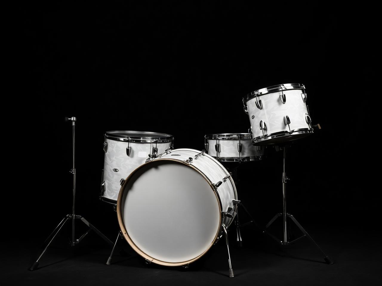 Vintage 1960s four-piece drum kit with pearl wrap finish, chrome hoops and lugs, photographed on a black backdrop